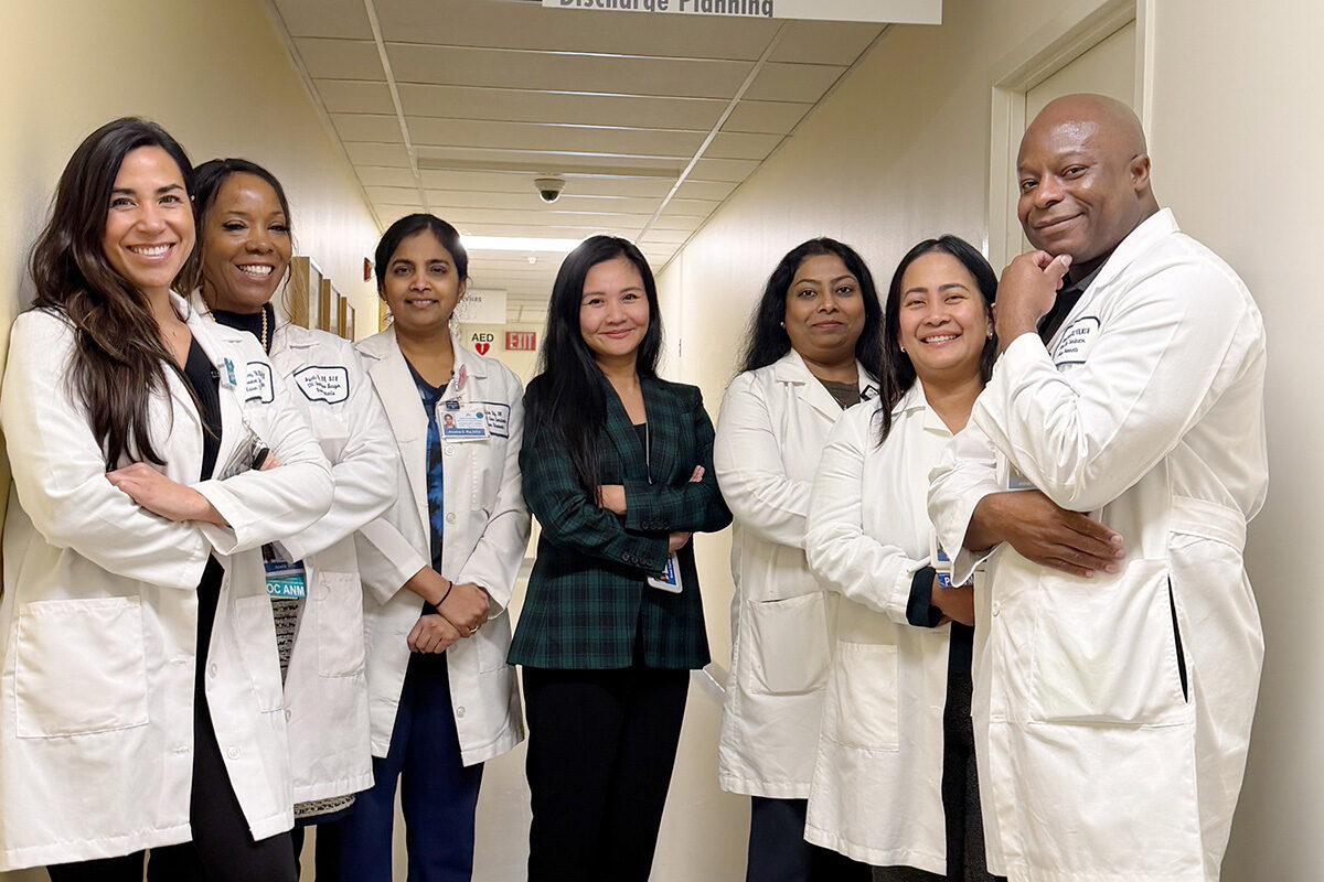 A group of nurses smiling in a hospital hallway.