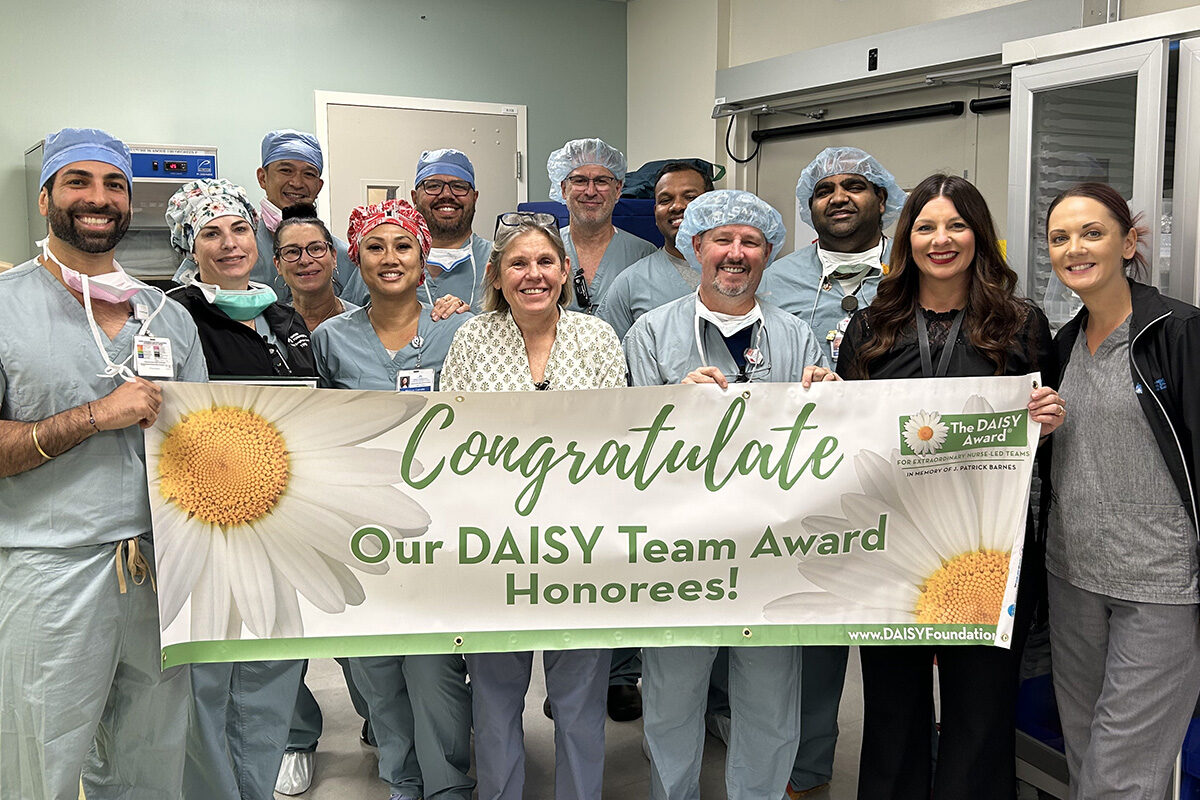 Sacramento nurses gather holding a DAISY team award banner