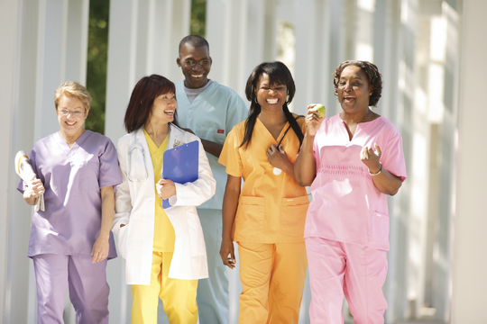 Stock image of nurses in colorful scrubs walking outside smiling.