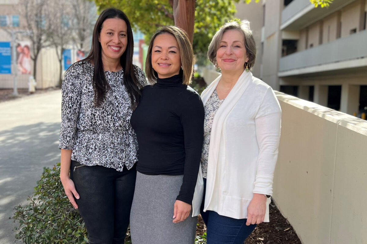 Nurses outside smiling by a tree