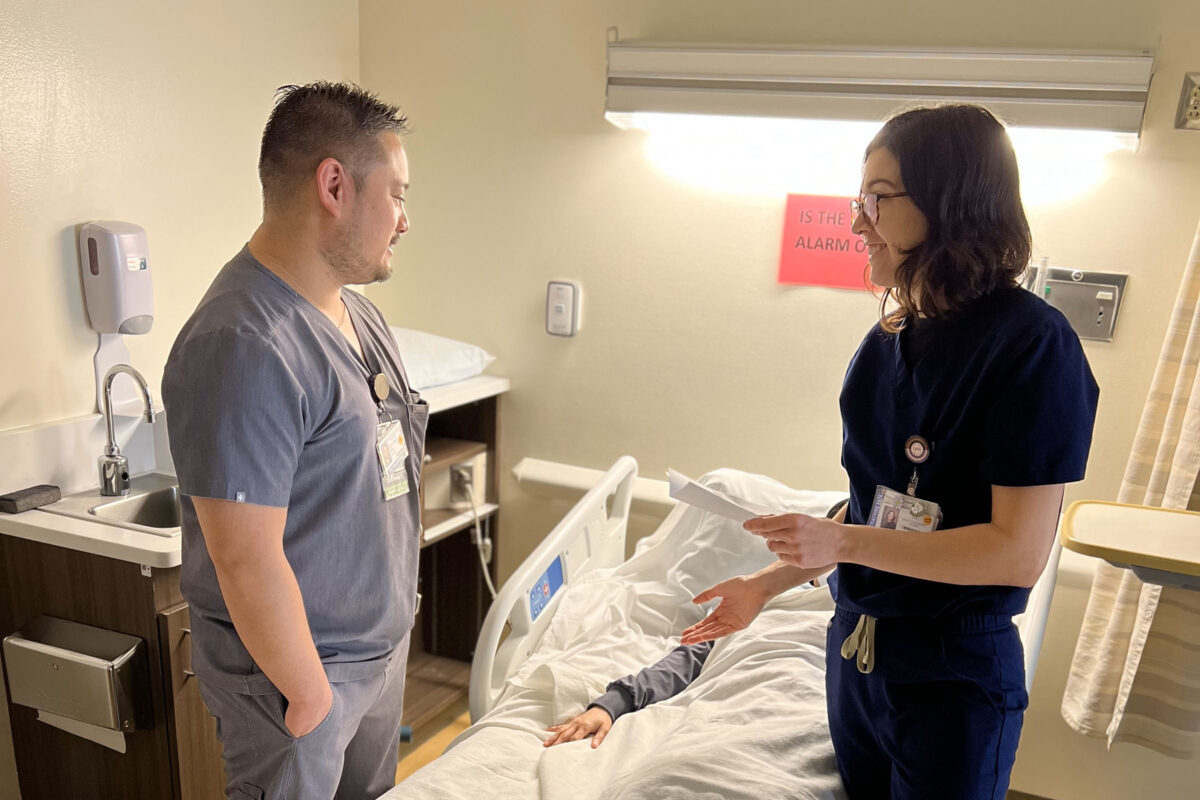 2 nurses talking at the bedside