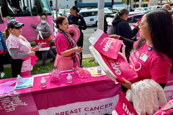 Nurse hands out pink bags at breast cancer awareness event