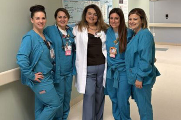 5 nurses smiling in the hallway