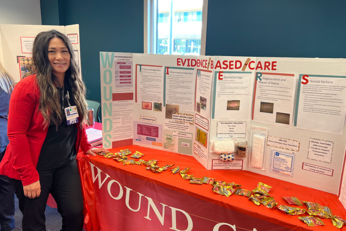 Nurse Melanie Baccay in front of a poster