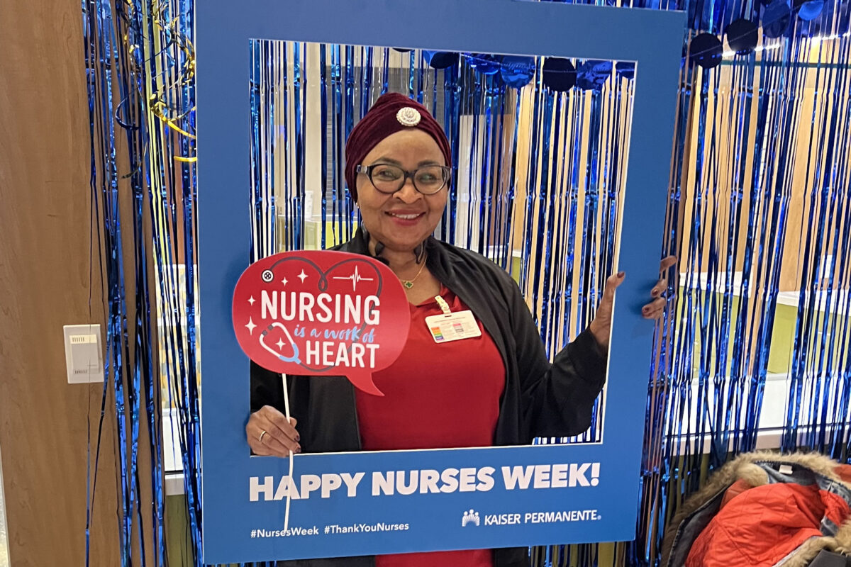 Nurse smiling with Happy Nurses Week sign