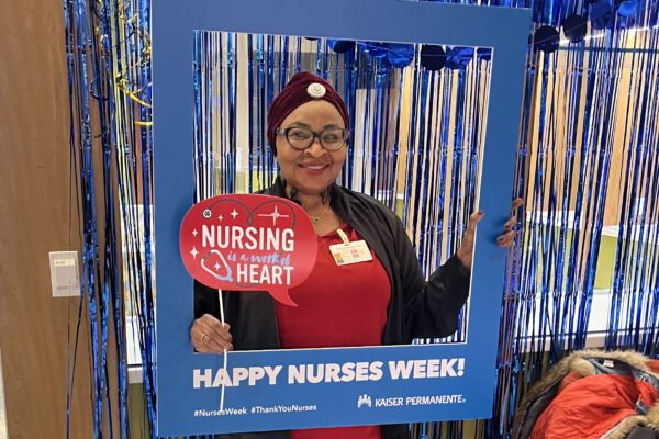 Nurse smiling with Happy Nurses Week sign