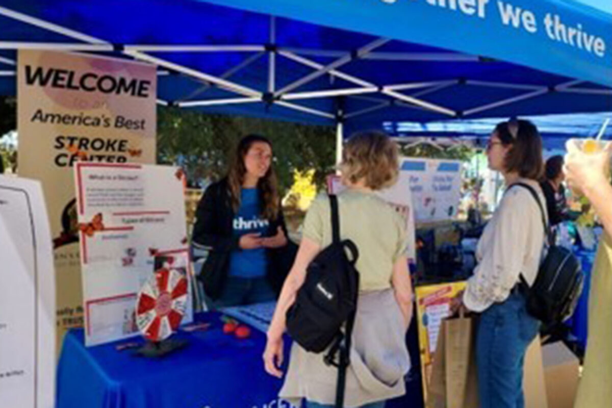 Nurse talking to two people at a health fair