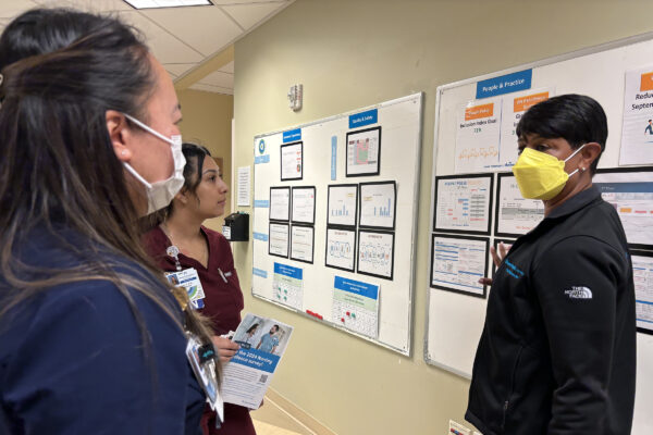 Sharon Hampton speaking with 2 nurses at the visibility board.