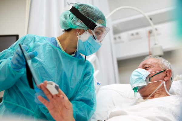 Hospital COVID One nurse showing a framed photograph of a relative to a COVID patient.