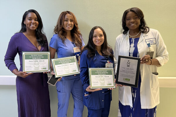Four nurses smiling holding an award