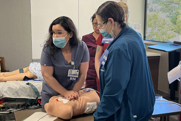 Nurse doing chest compressions on a dummy.