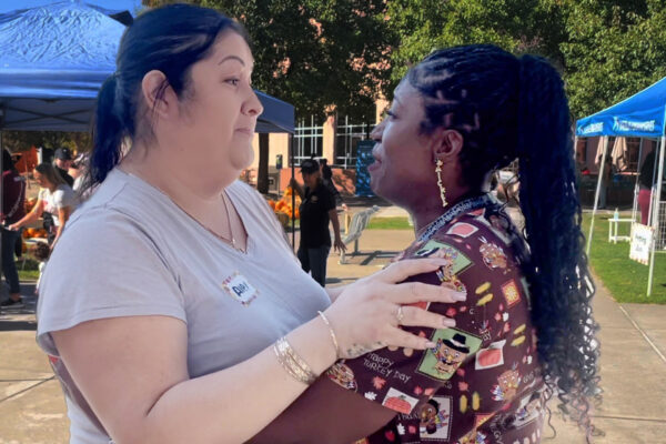 A nurse and the parent of a NICU baby share a hug.