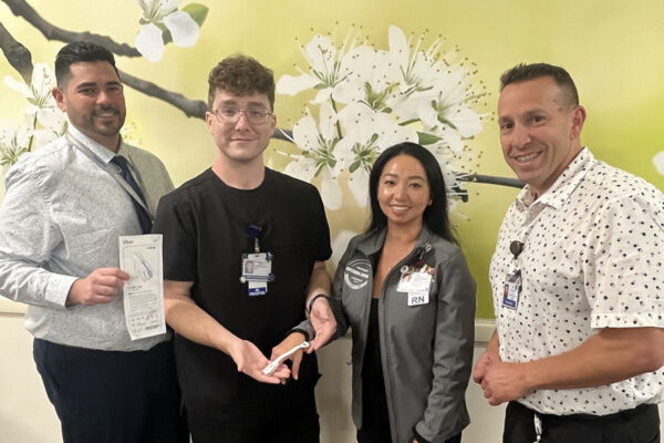 4 nurses smiling while holding a pulse oximeter