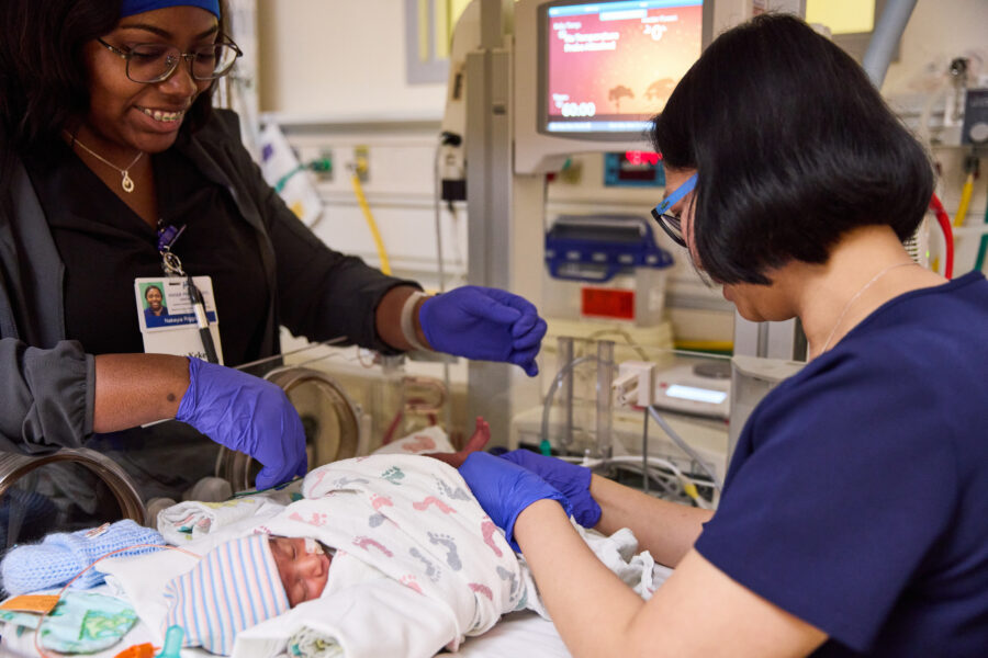 2 nurses in the nicu caring for a baby.