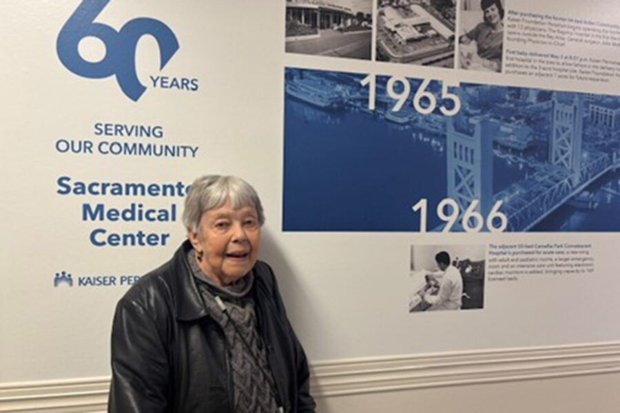 Dorola Haley, RN in front of a 60 year milestone graphic at the Sacramento Medical Center.
