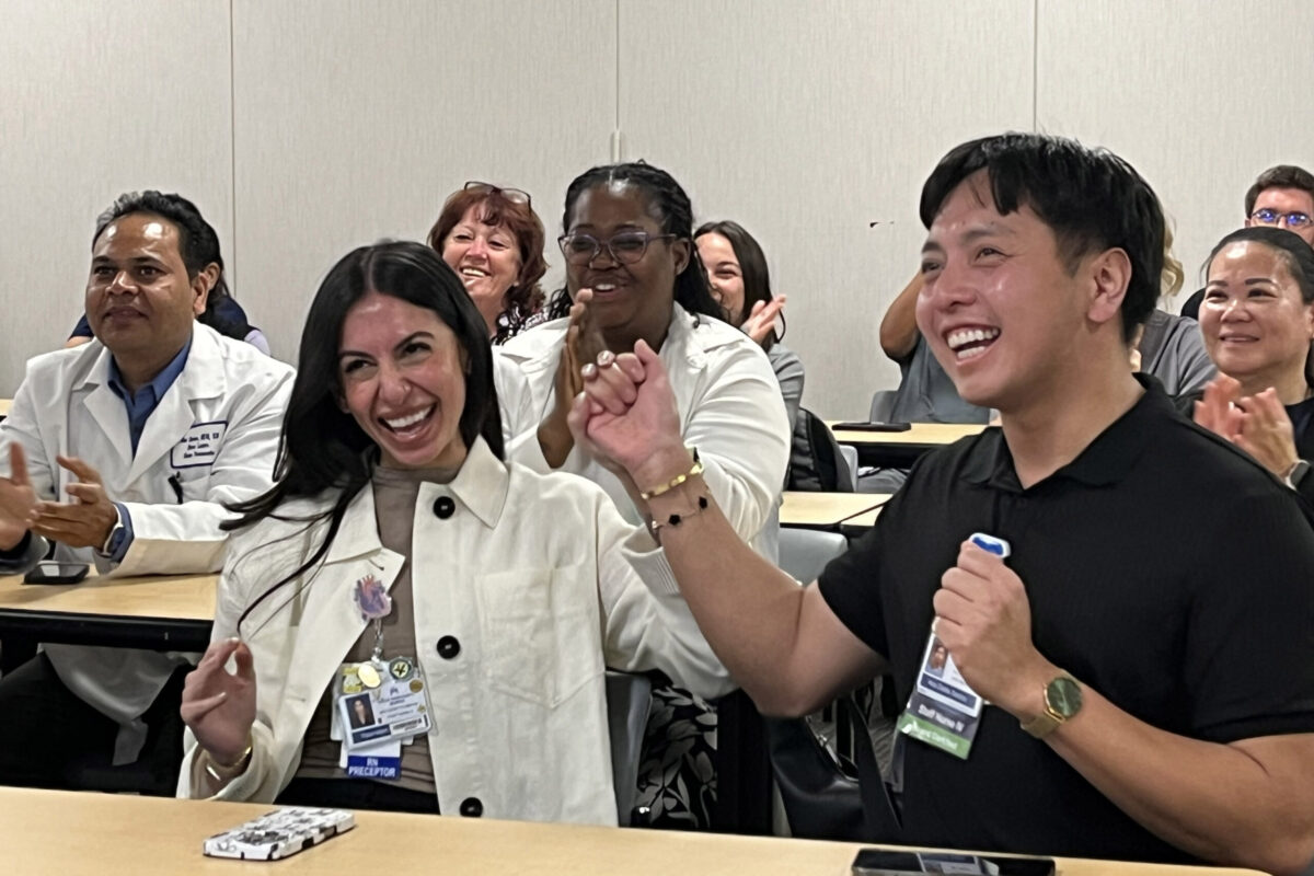 Two nurses cheering with nurses around them.