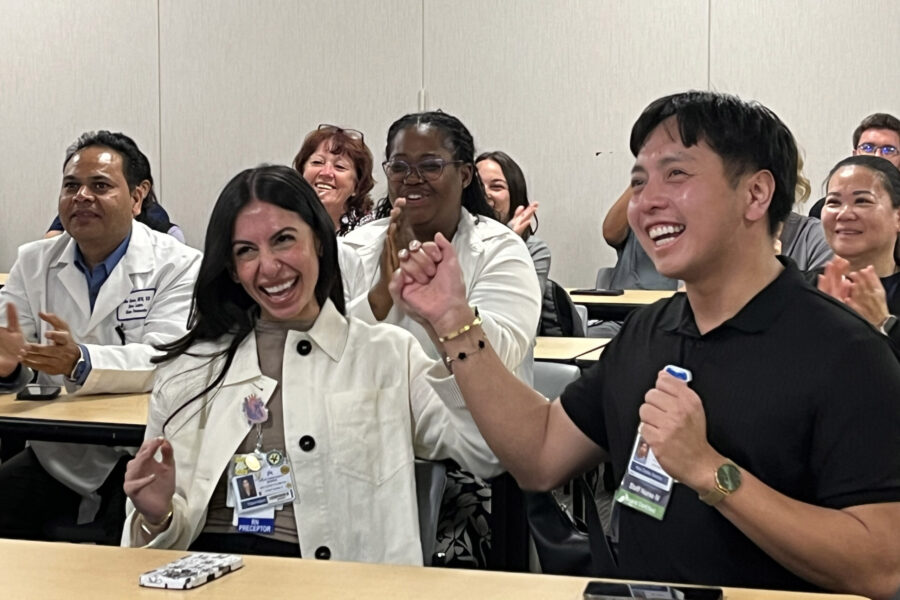 Two nurses cheering with nurses around them.