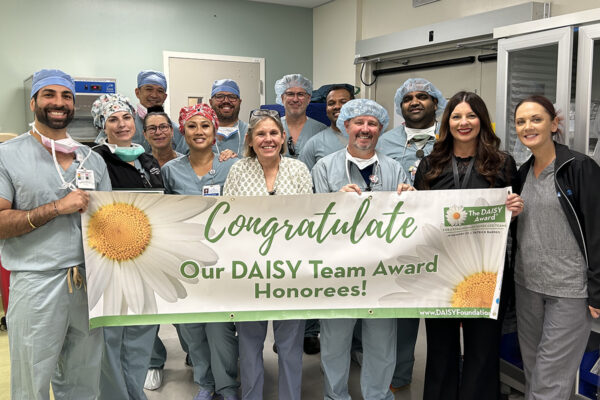 A group of interventional radiology team members holding a DAISY team award banner