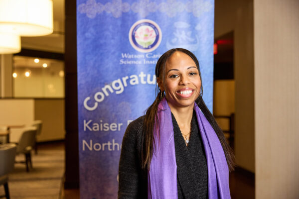 Nurse Amanda Sayaseng in front of a purple banner.