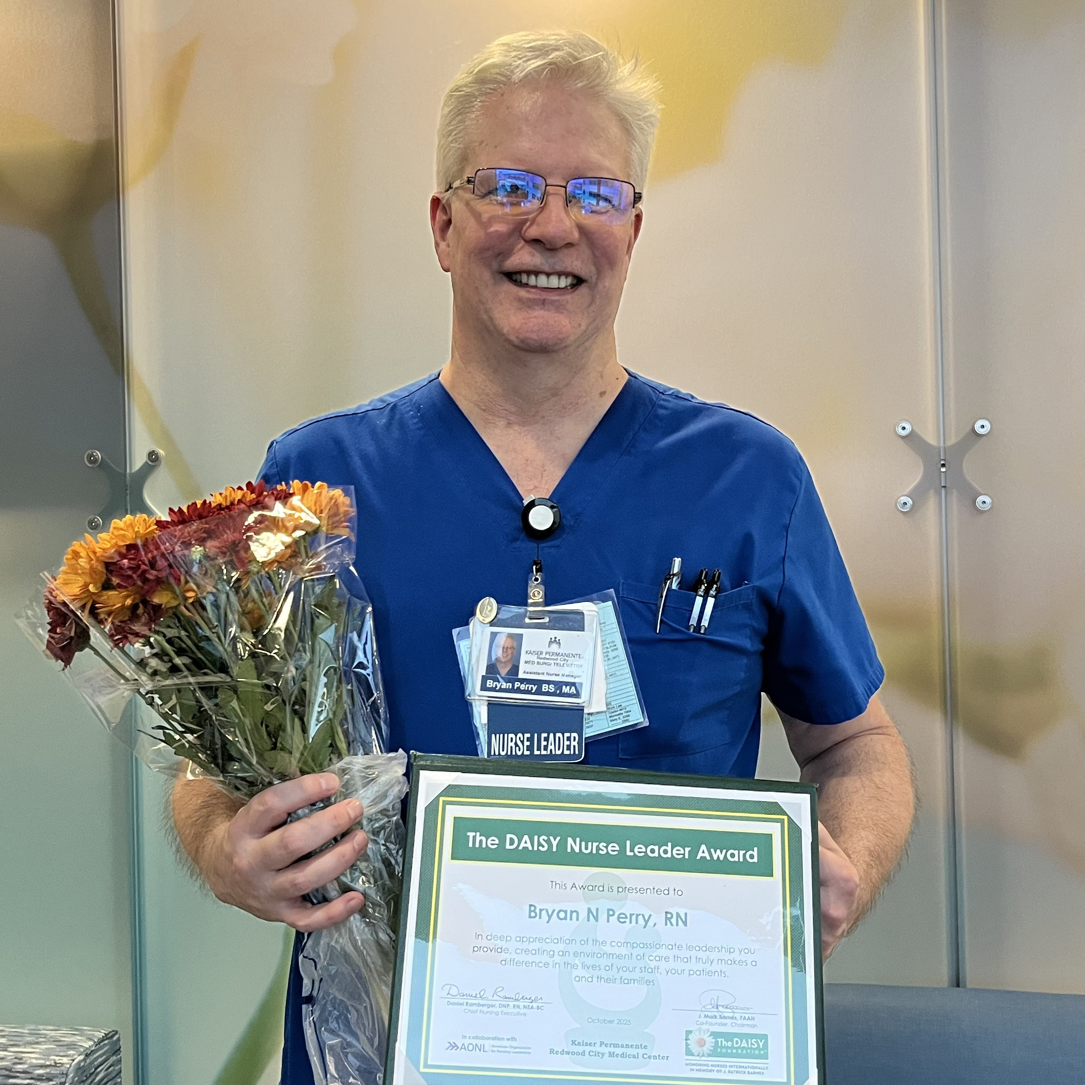 Bryan Perry holding flowers and a DAISY award