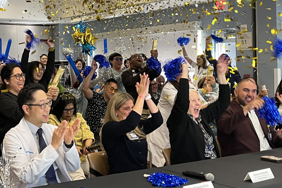 A group of nurses in a conference room cheering and confetti flying in the air.