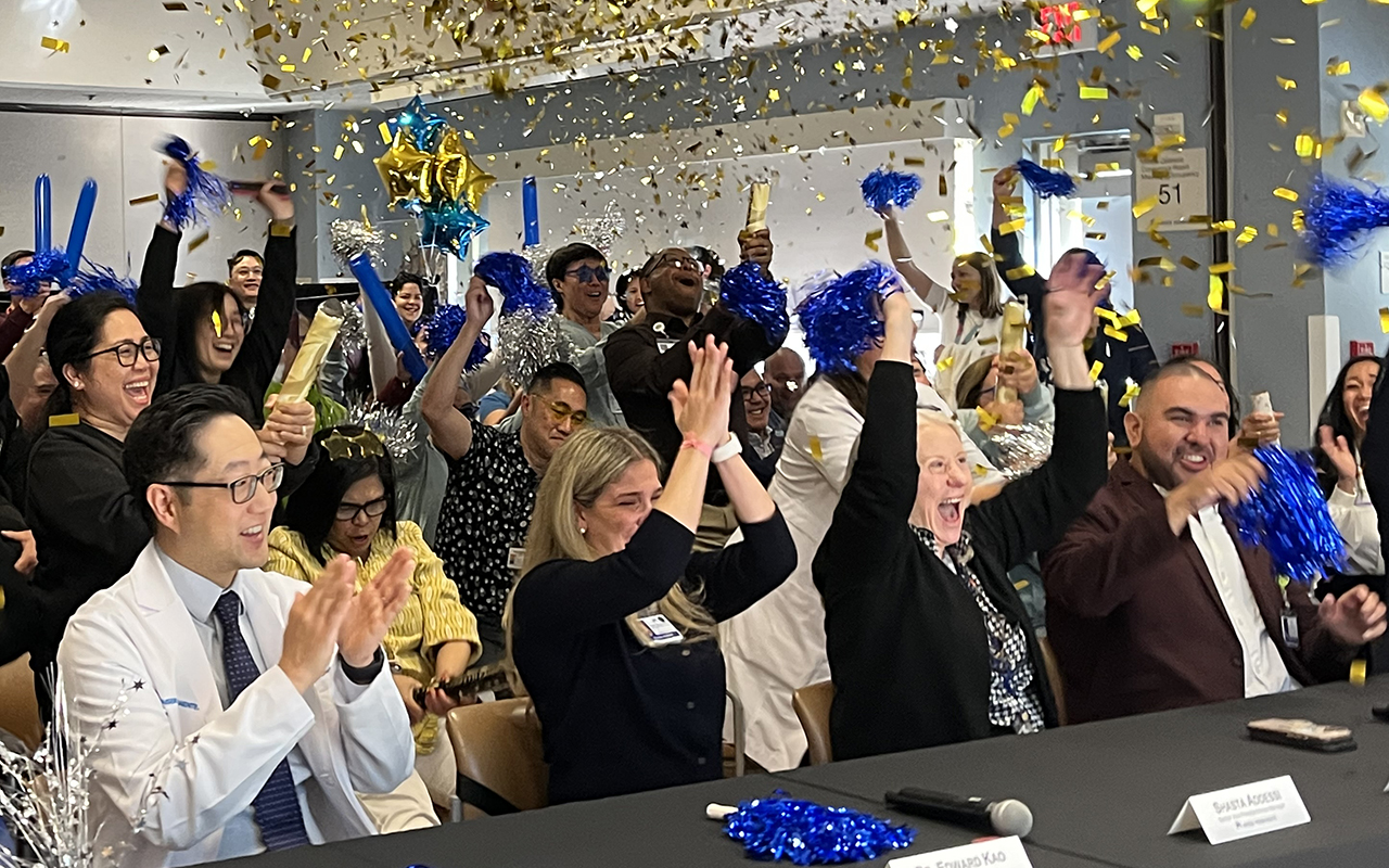 A group of nurses in a conference room cheering and confetti flying in the air.