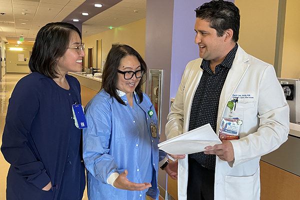 Mark Lee at right speaking to two nurses at the Redwood City Medical Center.
